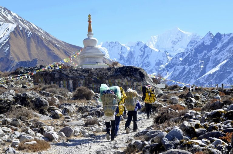 Porter carrying loads on the Everest Base Camp trail — tipping guides and porters is an important part of EBC trek etiquette